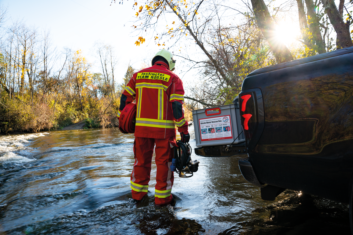 Feuerwehrmann steht im Hochwasser mit Tauchpumpe und Feuerwehrschlauch in der Hand