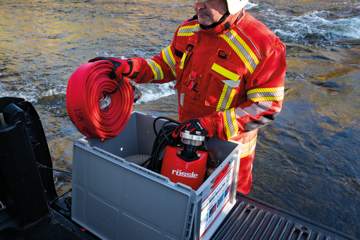 Feuerwehrmann nimmt Feuerwehrschlauch und Rössle Flachabsaugpumpe FLAT-ROSS aus der Water Rescue Box